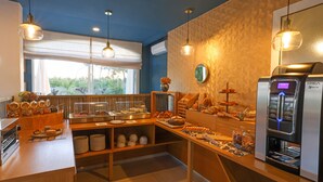 Un buffet de petit-déjeuner proposant une variété d’aliments, une machine à café et une vue sur la verdure environnante.