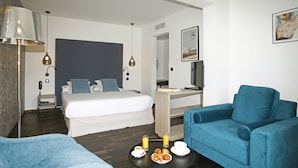 Une chambre d’hôtel moderne avec un lit, un bureau, un canapé bleu et une table sur laquelle sont disposés des articles pour le petit-déjeuner.