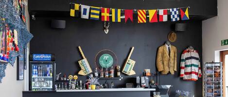 A bar area with a counter, multiple guitars, a jukebox, and a sign for a song contest exhibition.