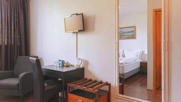 A hotel room with a desk, chair, and a large mirror.