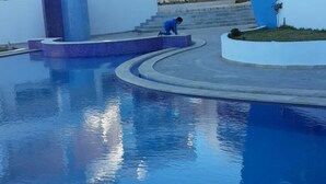 A modern building with a pool area, featuring a curved pool and a person walking near the pool. - Hergla Diamond (Hergla)