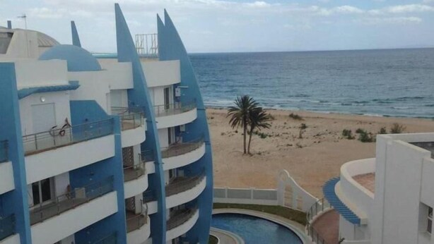 A multi-story hotel with balconies overlooking a beach and a pool area. - Hergla Diamond (Hergla)