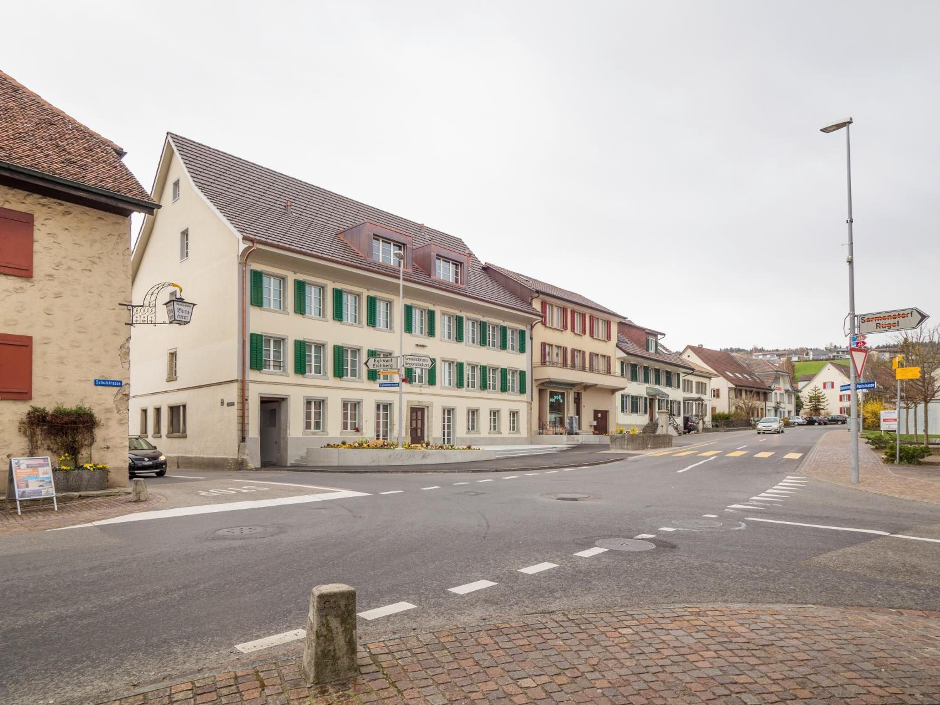 Straatbeeld met traditionele Europese gebouwen, een heldere weg en richtingwijzers.