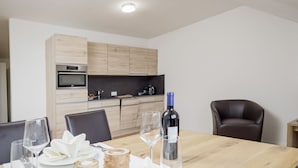A dining area with a wooden table set for two, a bottle of wine, and a candle. - Hotel & Apartments Bären (Seengen)