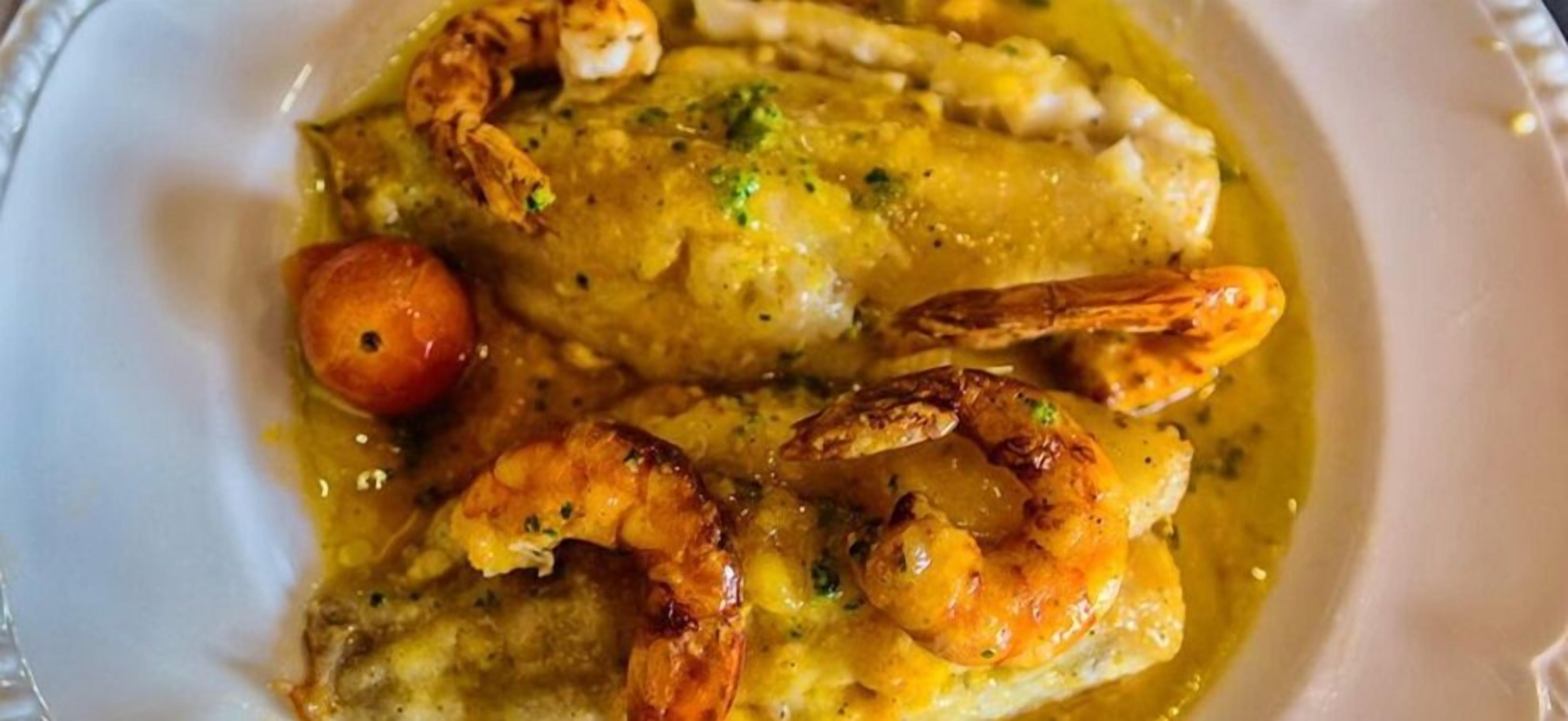 A dish with shrimp and chicken in a creamy sauce, served in a white bowl.