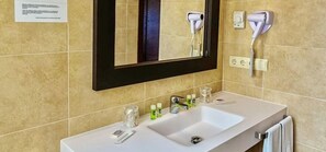 A hotel bathroom with a white sink, a mirror, and two hair dryers mounted on the wall. - Hotel Balneari de Vallfogona (Vallfogona de Riucorb)
