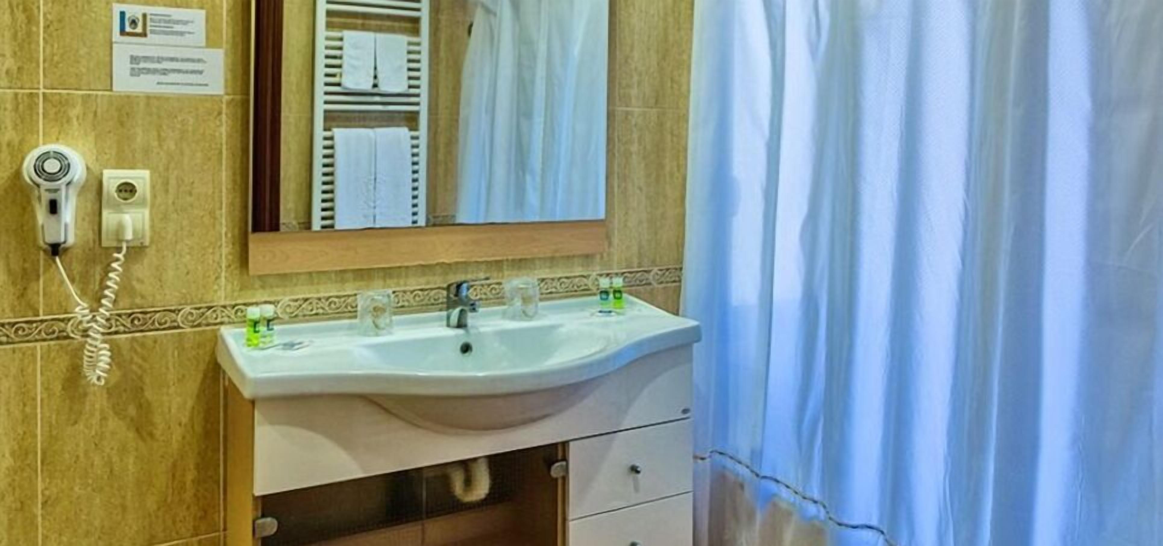 Un baño con lavamanos, espejo y perchero para toallas.