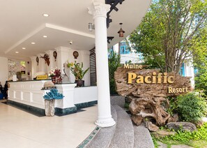 A reception area with a sign for Muine Pacific Resort, a reception desk, and a large tree. - Sunday Pacific Beach Resort Muine (Mui Ne)