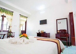 A hotel room with a bed, a desk, a chair, a television, and a mirror. - Sunday Pacific Beach Resort Muine (Mui Ne)