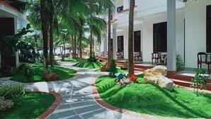 A resort courtyard with palm trees, a central pathway, and outdoor seating areas. - Pacific Beach Resort (Mui Ne)