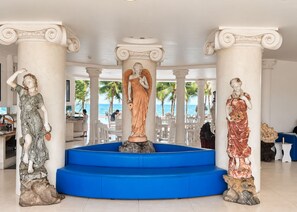 A lobby with three statues, a blue staircase, and a view of the beach. - Sunday Pacific Beach Resort Muine (Mui Ne)