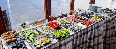 A buffet table with various food items and a view of a snowy landscape through a window.