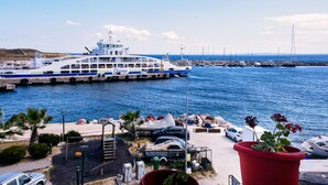 Un ferry atracado en un muelle, con vistas al mar y coches aparcados.