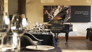 A dining area with a piano, wine glasses, and a poster on the wall. - HOTelarnia (Puszczykowo)