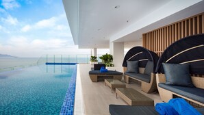 Eine moderne Lounge-Bereich im Freien mit Pool, Sitzgelegenheiten und Blick aufs Meer.