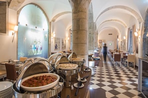 Een restaurantruimte in een hotel met diverse buffetten, een receptiebalie en een uitcheckbalie.