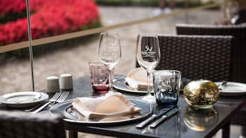 Une table à manger dressée avec des assiettes, des couverts, des verres et un saladier décoratif.