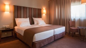 Une chambre d’hôtel avec un grand lit, deux lampes de chevet, une chaise et une petite table.