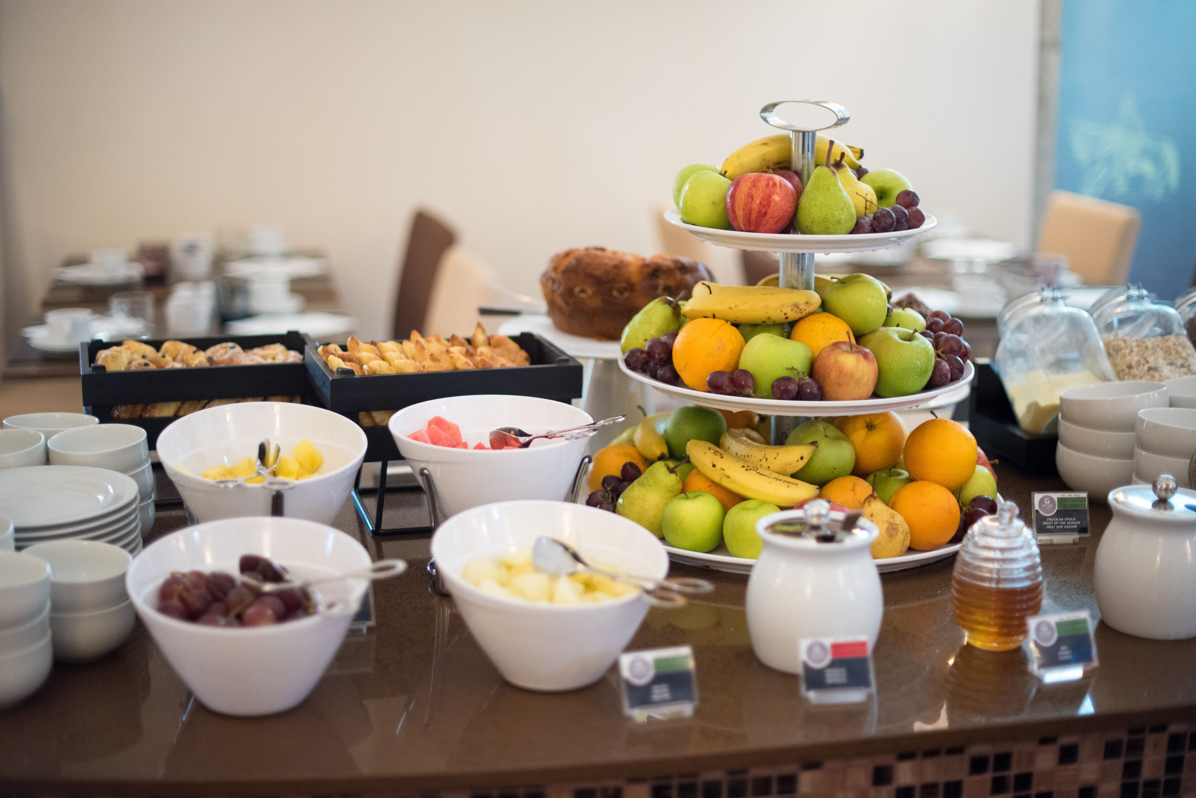 A buffet with various food items including fruits, pastries, and breakfast options.