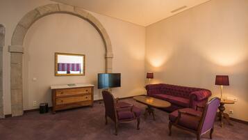 A living room with a stone arch, a television, a sofa, two armchairs, a coffee table, and lamps.