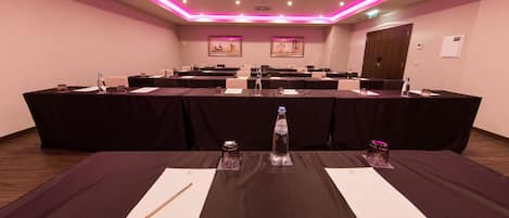 Un salón de conferencias con varias mesas, cada una con tarjetas de identificación, botellas de agua y bolígrafos.