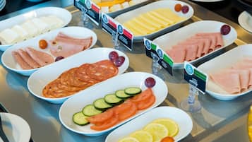 A buffet with various food items including cheeses, meats, and fresh fruits.