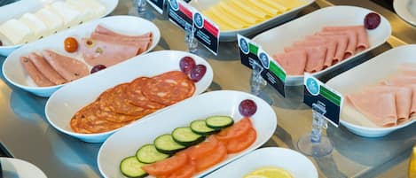 Un buffet proposant une variété de plats, notamment des fromages, des viandes et des fruits frais.
