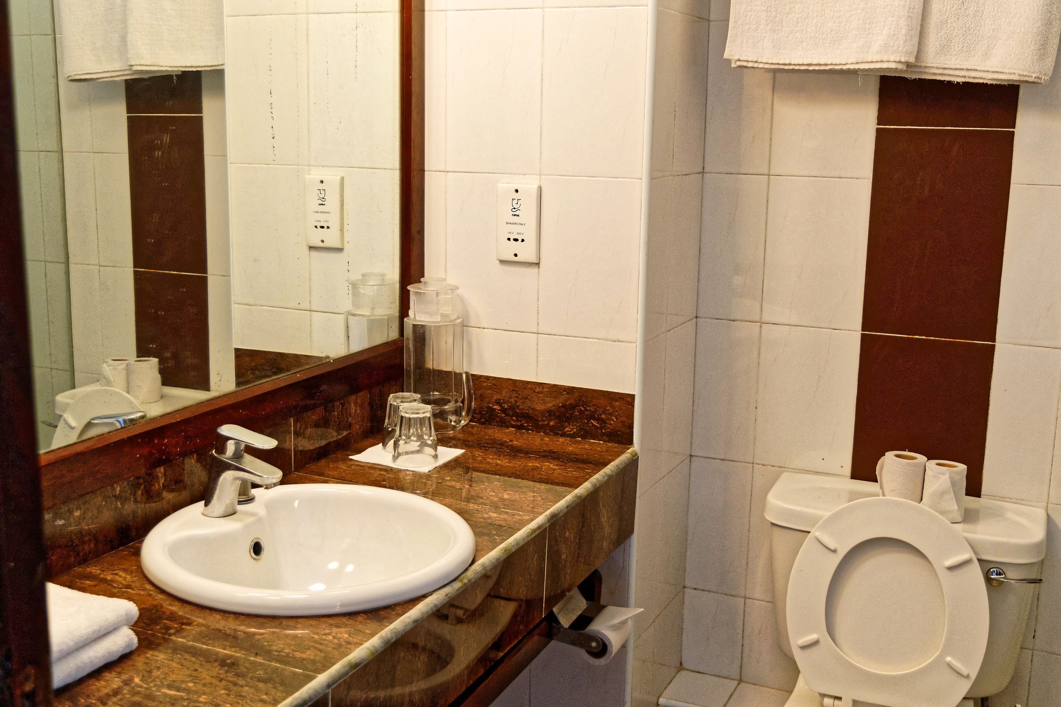 Et badeværelse med vask, spejl og toilet.
