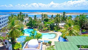 Een resort met een zwembad, palmbomen en uitzicht op de oceaan.