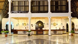 Een ruime lobby met een hoog plafond, een receptiebalie en meerdere kroonluchters.