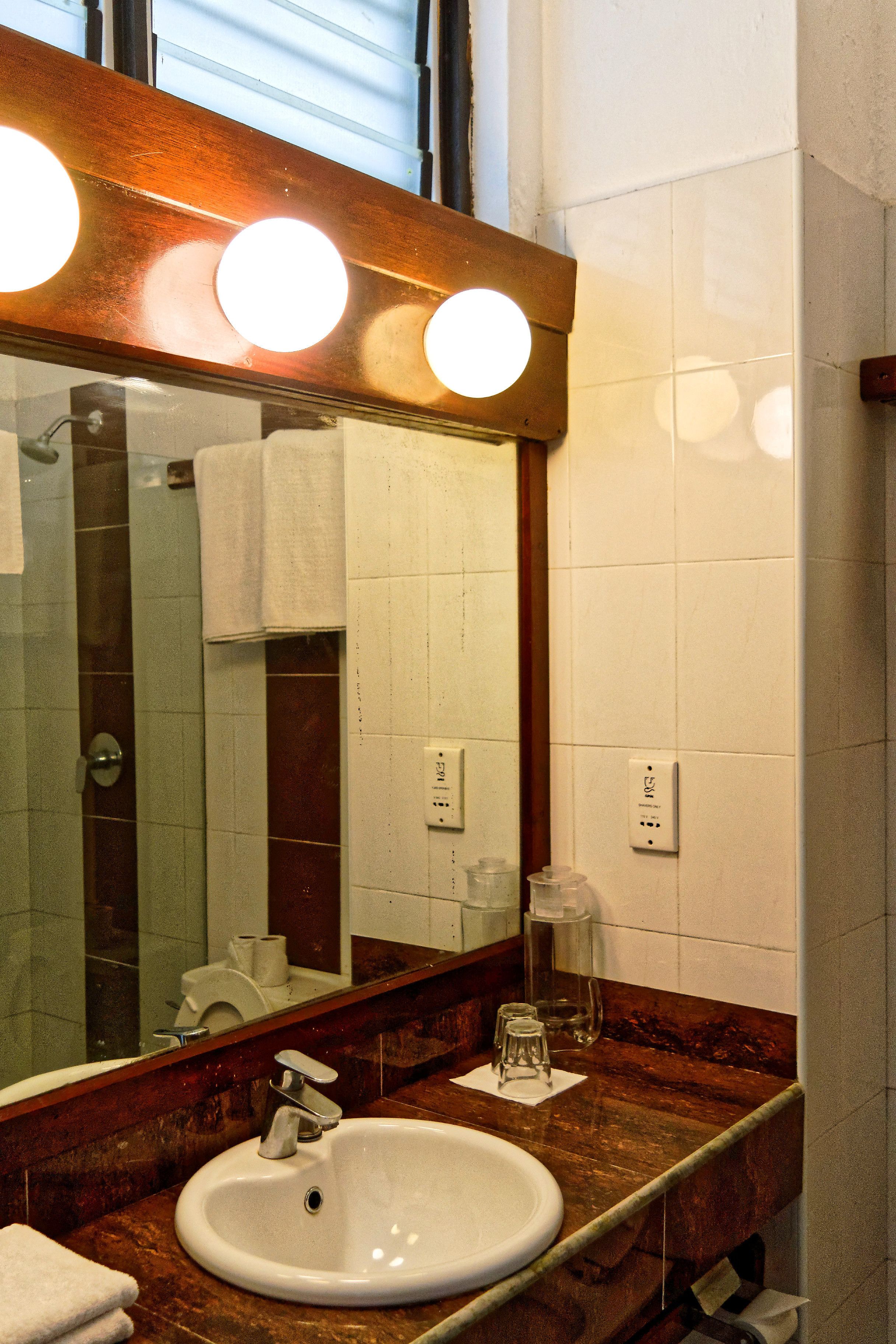 Un bagno con lavabo, specchio e portasciugamani.