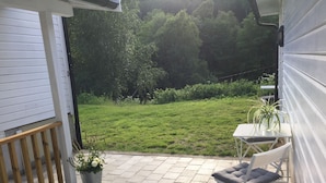 A patio with a table and chairs, a potted plant, and a view of a grassy area. - Otra Inn (Vennesla)
