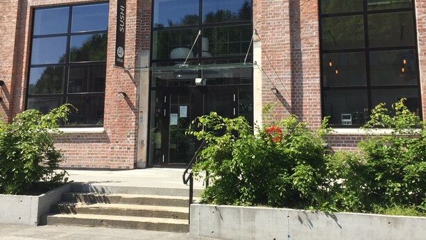 A brick building with large windows and a sign reading "SUSHI". - Otra Inn (Vennesla)