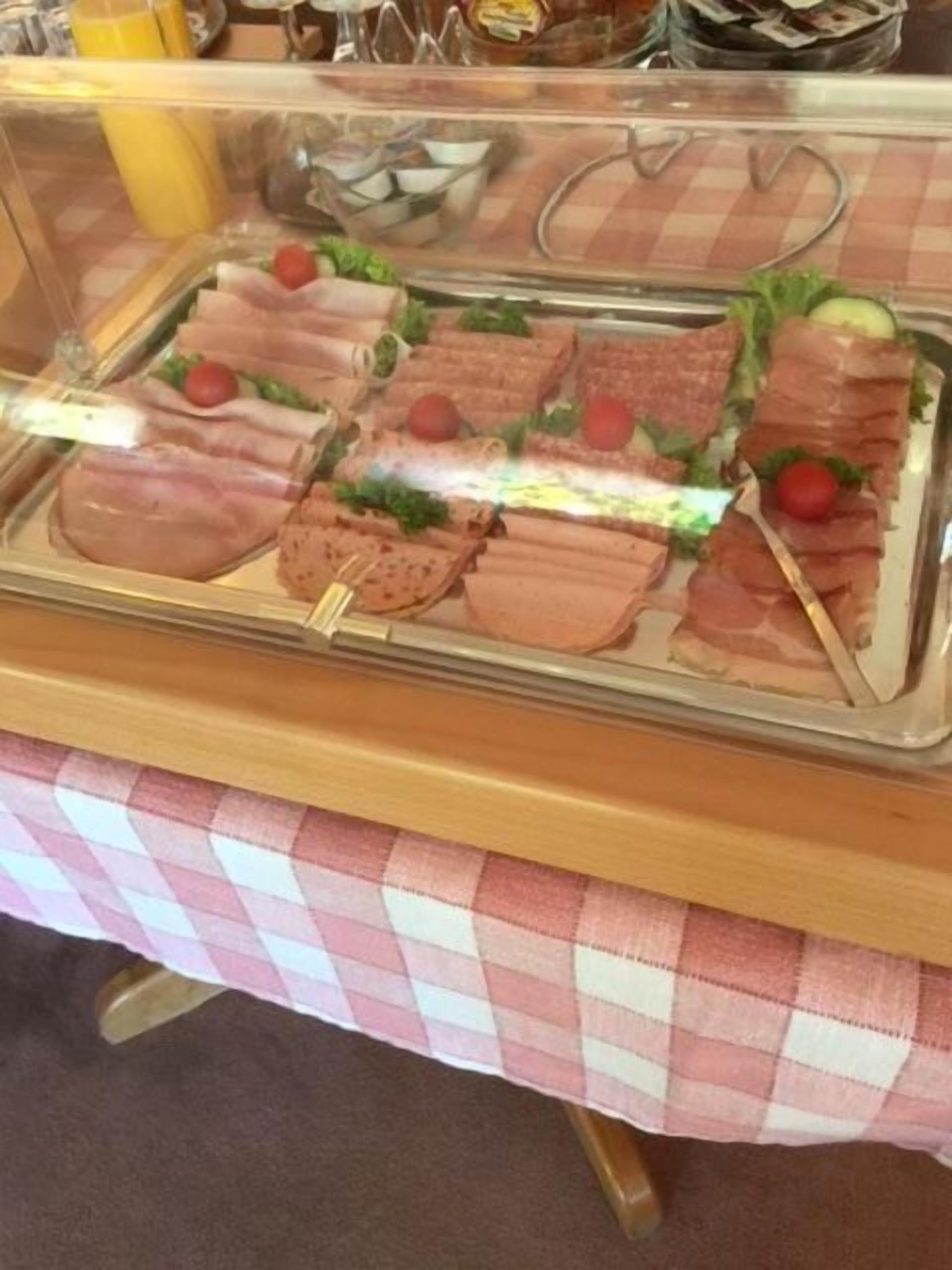 En buffet med forskellige retter, herunder sandwiches og salater, udstillet i et glasmontér.