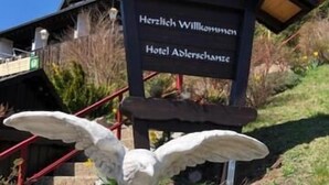 «Herzlich Willkommen Hotel Adlerschanze» -kyltti, jonka edessä on kotkan patsas.
