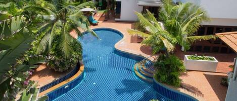 Alberca al aire libre, sombrillas en la alberca y camastros