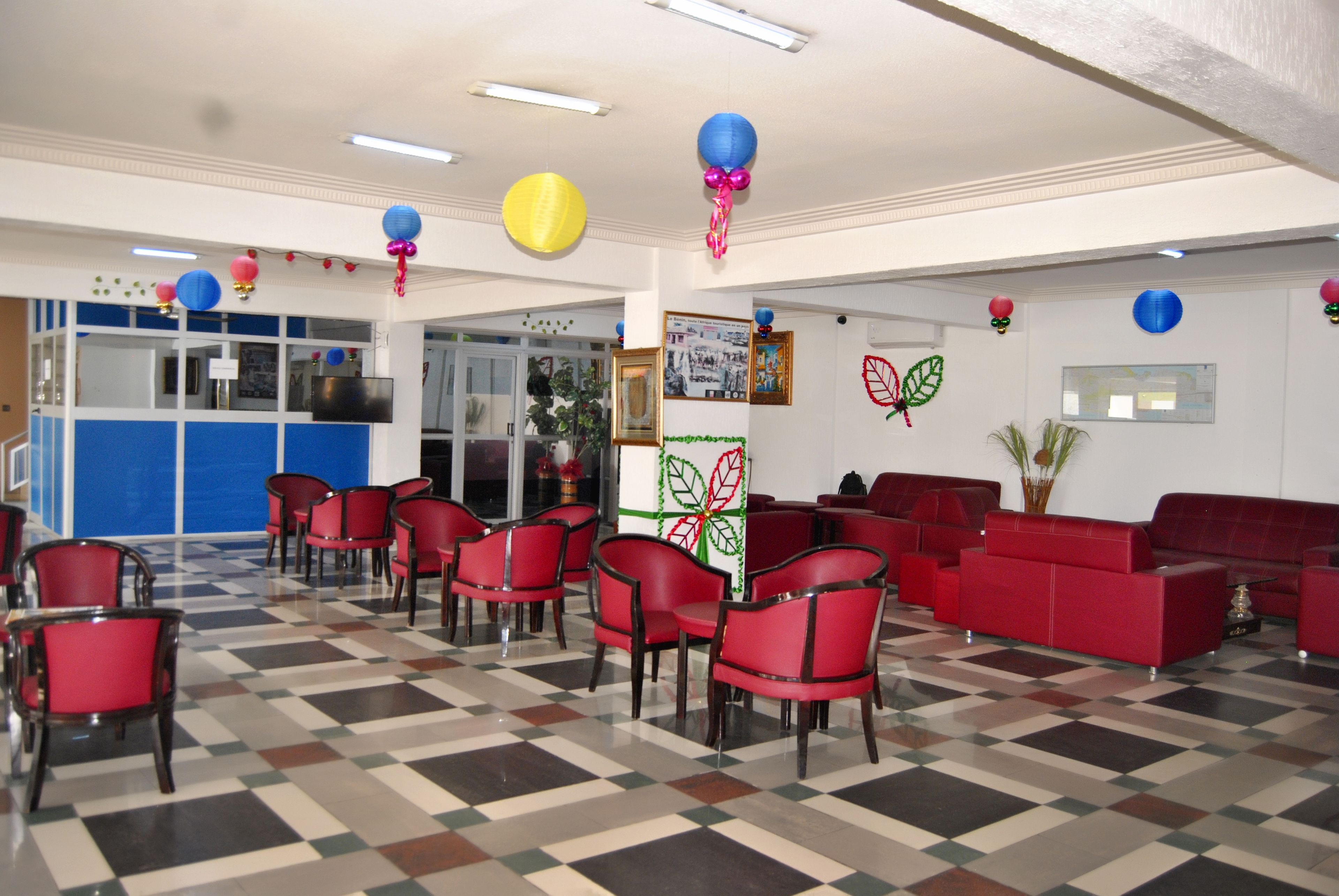 Eine Lobby mit roten Sesseln und Sofas, einem Schachbrettfußboden und Wanddekorationen, darunter ein Schmetterling und Ballons.