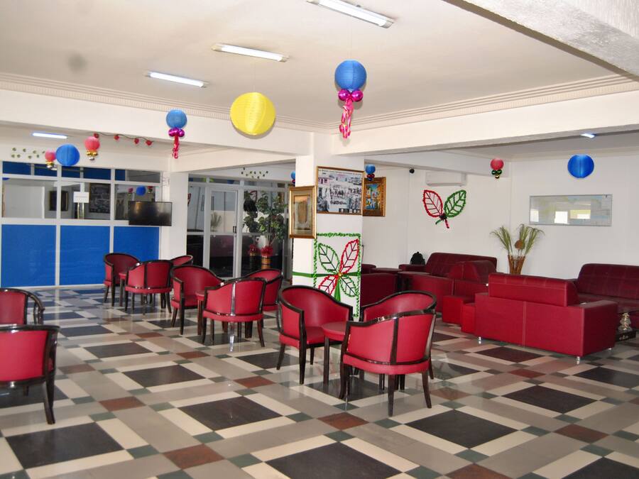 Eine Lobby mit roten Sesseln und Sofas, einem Schachbrettfußboden und Wanddekorationen, darunter ein Schmetterling und Ballons.
