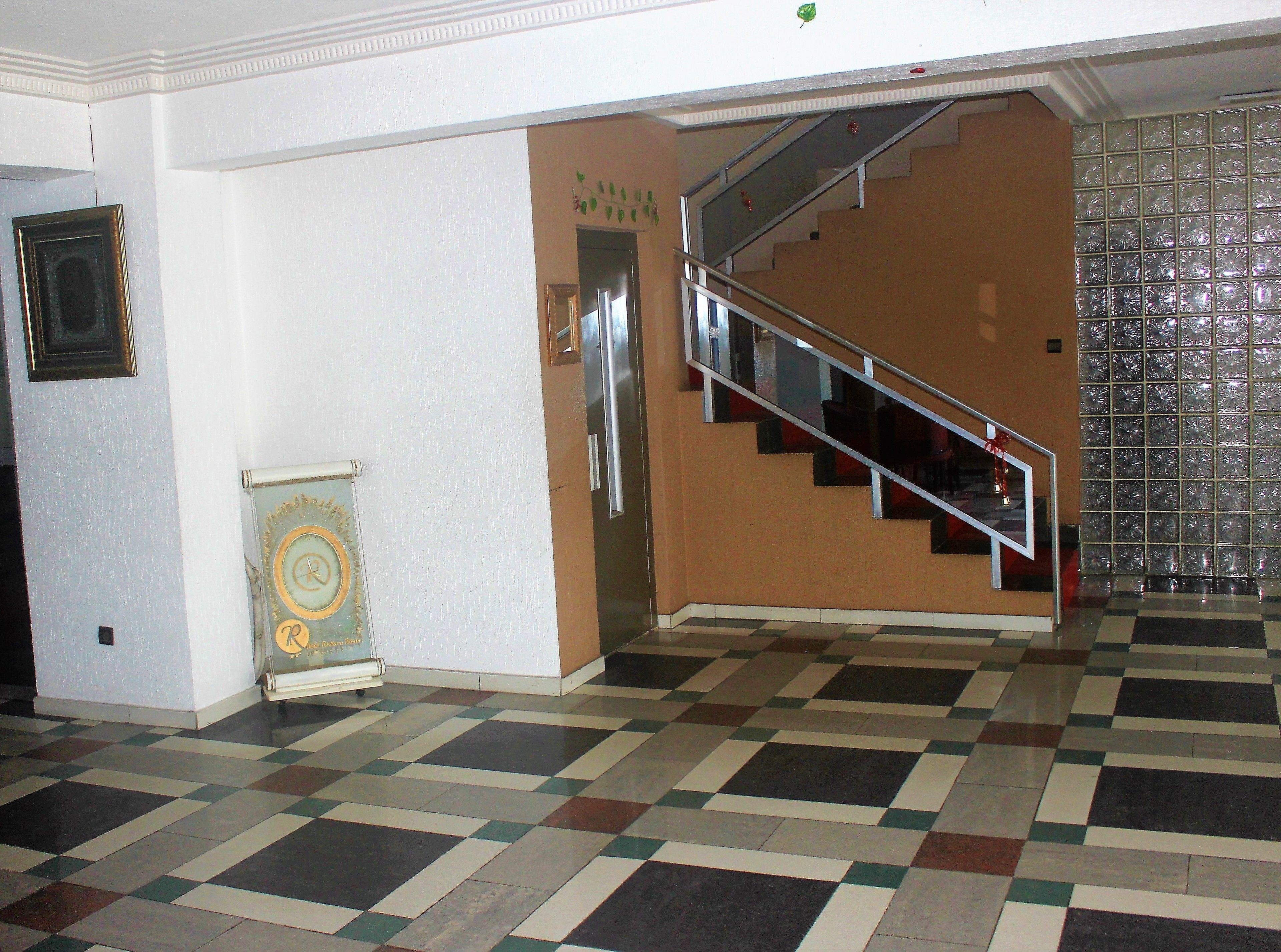 A staircase with a metal railing leading to a landing. The floor has a checkered pattern.