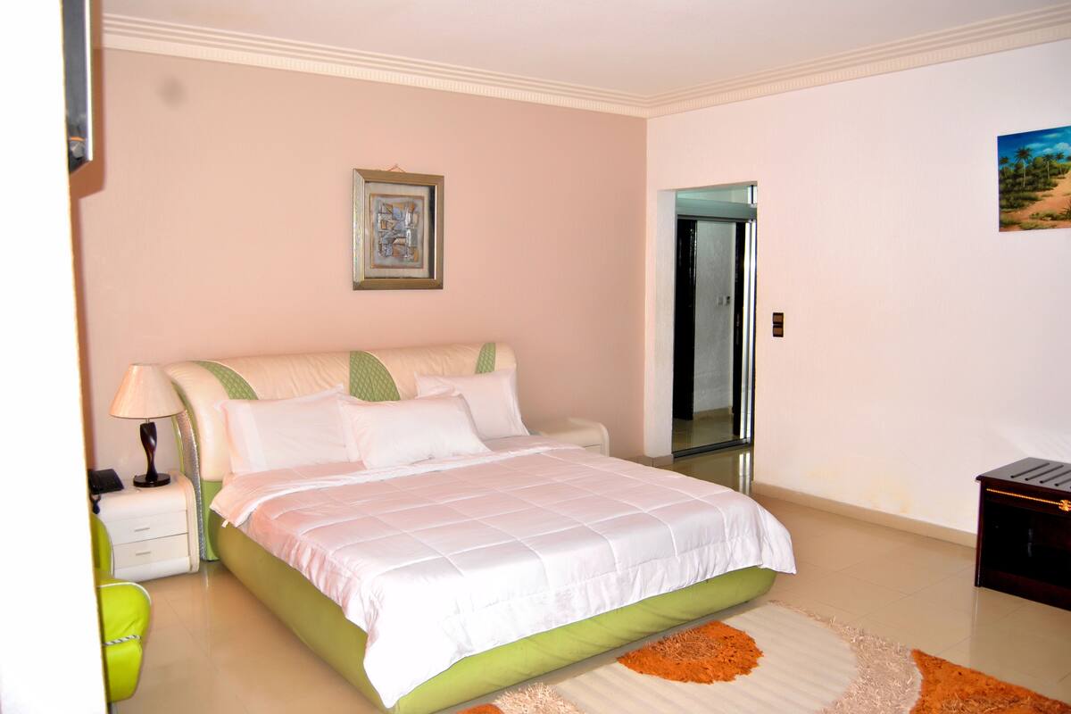 A bedroom with a bed, nightstand, lamp, and a mirror.