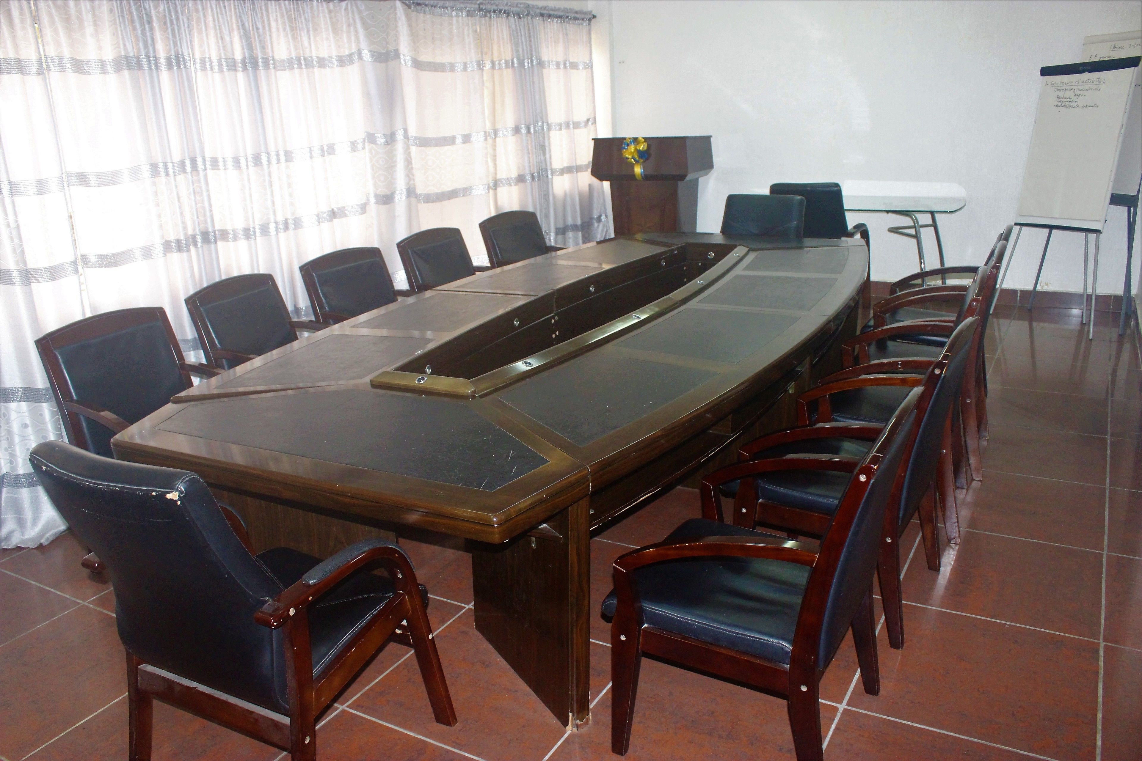 A conference room with a long table, chairs, a podium, and a whiteboard.