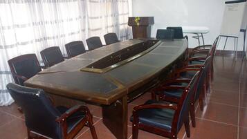 A conference room with a long table, chairs, a podium, and a whiteboard.