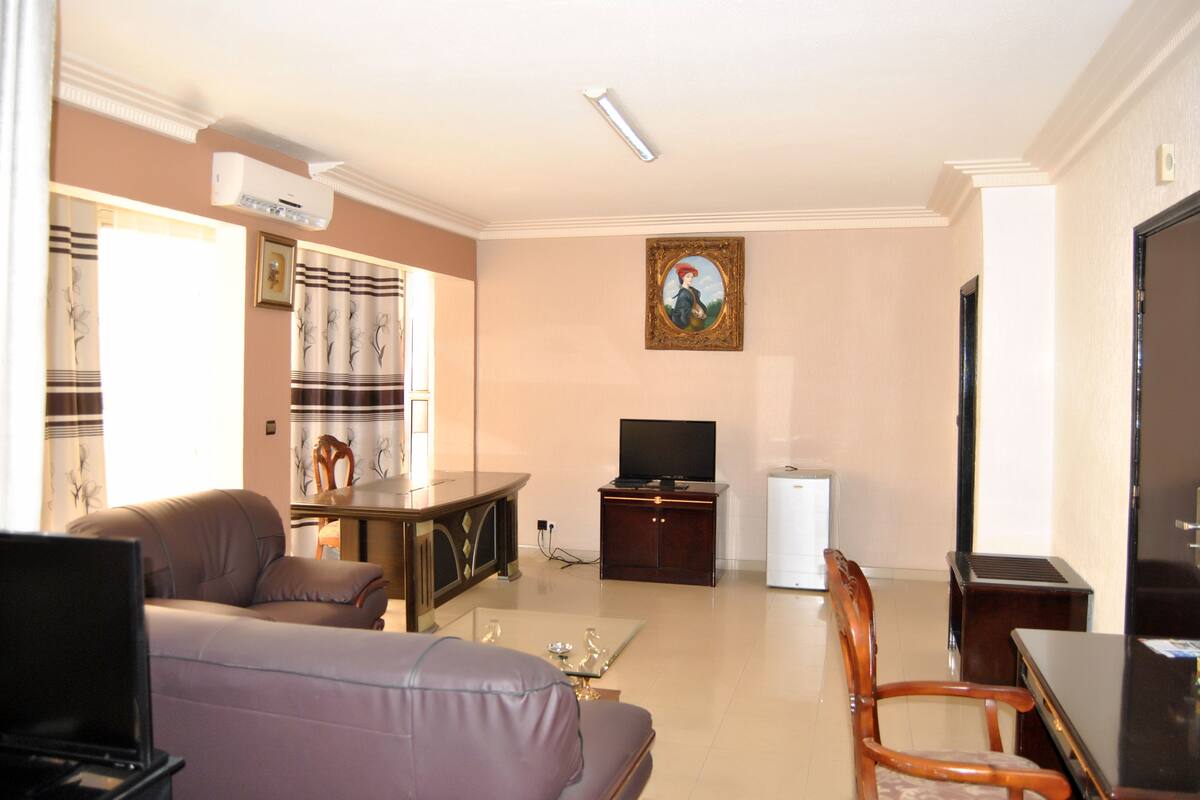 A living room with a sofa, TV, and a painting on the wall.