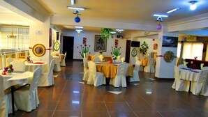Un salón de banquetes con varias mesas redondas cubiertas con manteles blancos y sillas.