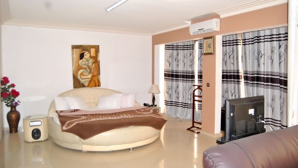 Una habitación de hotel con una cama, televisión, radio y un cuadro en la pared.