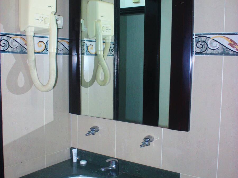Une salle de bain avec un lavabo vert, une serviette blanche et un miroir au-dessus du lavabo.