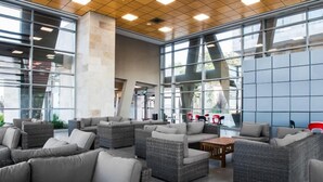 A spacious indoor seating area with wicker furniture and large windows. - HI  Haifa Hostel (Haifa)