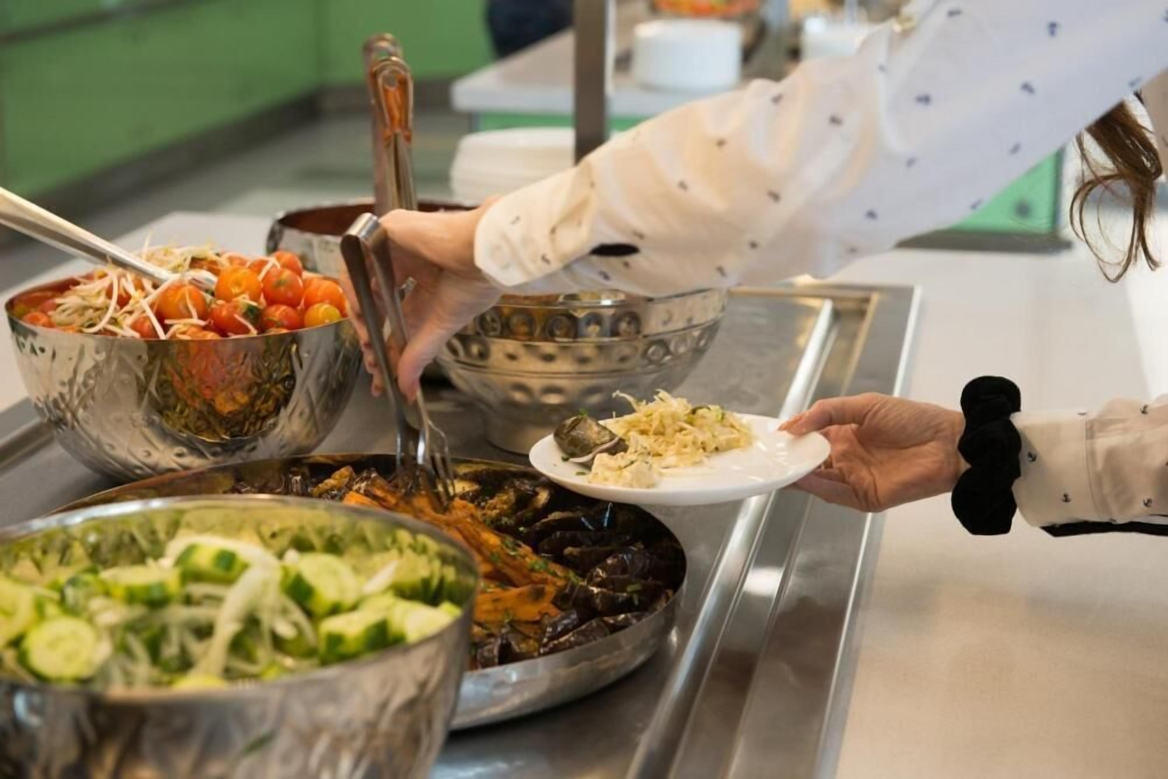 A buffet setup with various dishes including a salad, a pasta dish, and a seafood dish.