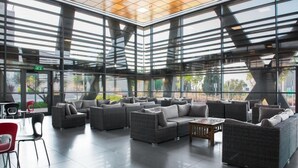 A modern lounge area with multiple seating options, including sofas and chairs, arranged around a central coffee table. - HI  Haifa Hostel (Haifa)