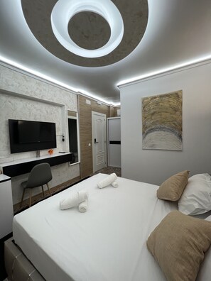 A modern hotel room with a large bed, a desk with a flat-screen TV, a chair, and a ceiling with a circular skylight. - Hotel Galeón Boutique (Calpe)